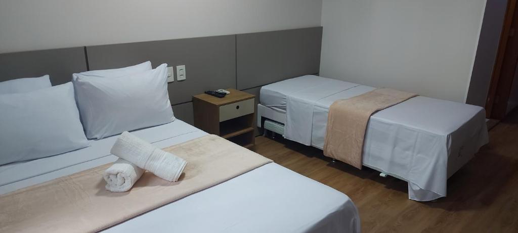 a hotel room with two beds with white sheets at Flat - Comfort Hotel - Taguatinga in Brasilia