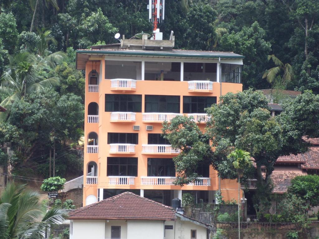 an orange building with trees in front of it at Majestic Tourist Hotel in Kandy