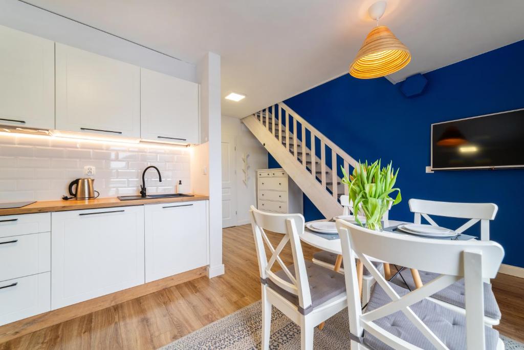 a kitchen and dining room with white cabinets and a blue wall at Apartamenty Białe Piaski in Jastarnia