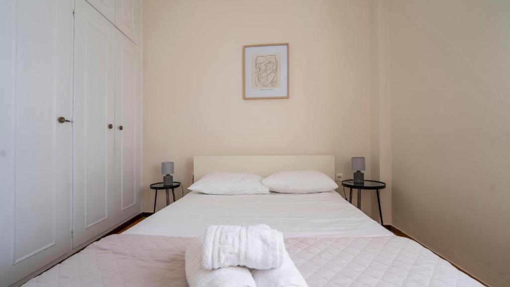 a white bedroom with two beds with towels on them at Cozy Apartment in Hermoupolis in Ermoupoli