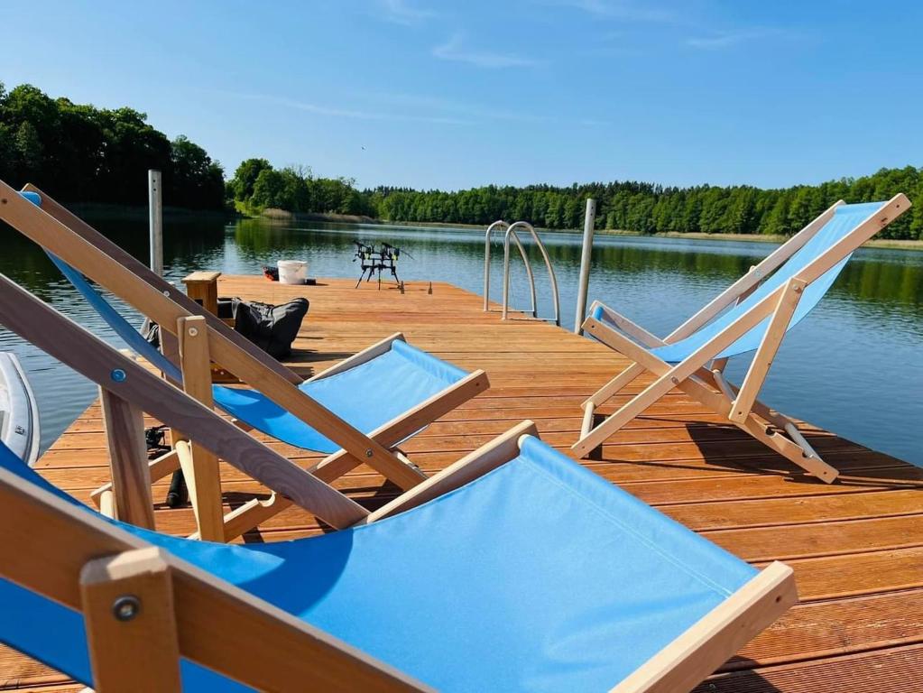 dos sillas sentadas en un muelle en un lago en Nini House Swietajno, en Olecko