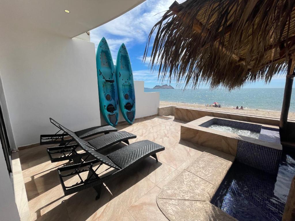 a room with chairs and a surfboard on the beach at Hermosa casa a la orilla del mar in Bahía Kino