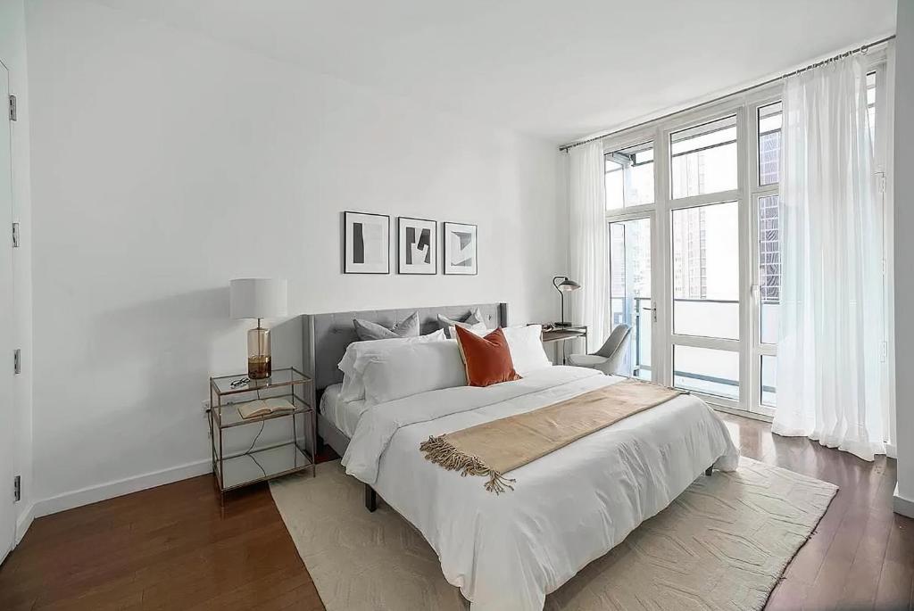 a white bedroom with a large bed and a window at FURNISHED Oversized 1 Bedroom with Home Office (Short-Term Available) in New York