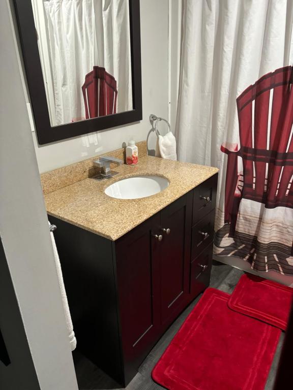 baño con lavabo y silla roja en Red door retreat guesthouse en Thorold