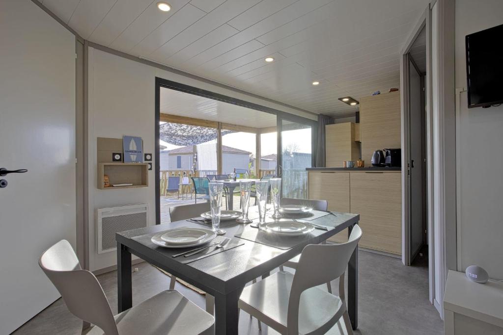 una sala da pranzo con tavolo nero e sedie bianche di Le Chalet Aquila - Welkeys a Saubrigues
