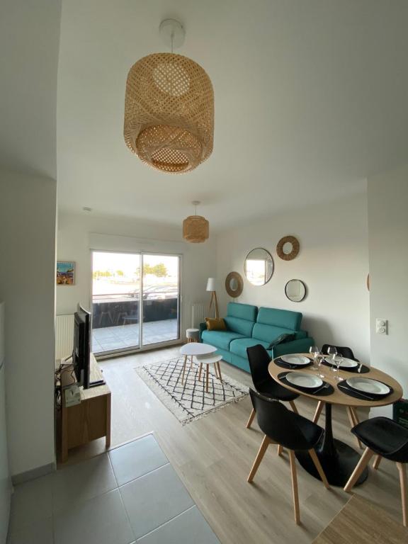 uma sala de estar com um sofá azul e uma mesa em Charme des quais, proche centre et plage em Dunkerque