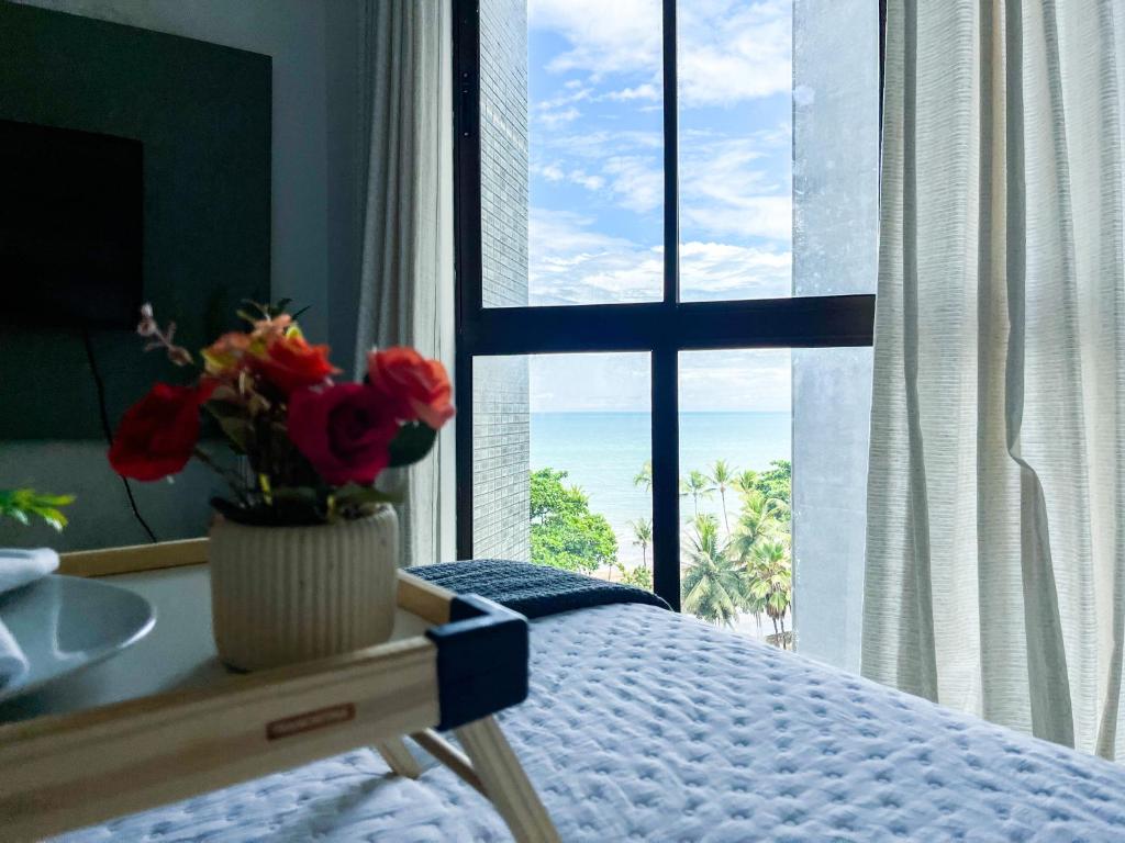 een slaapkamer met een bed en een raam met een vaas met bloemen bij Beira-mar Boa Viagem - Costa Vicentina by Bnb Flex in Recife