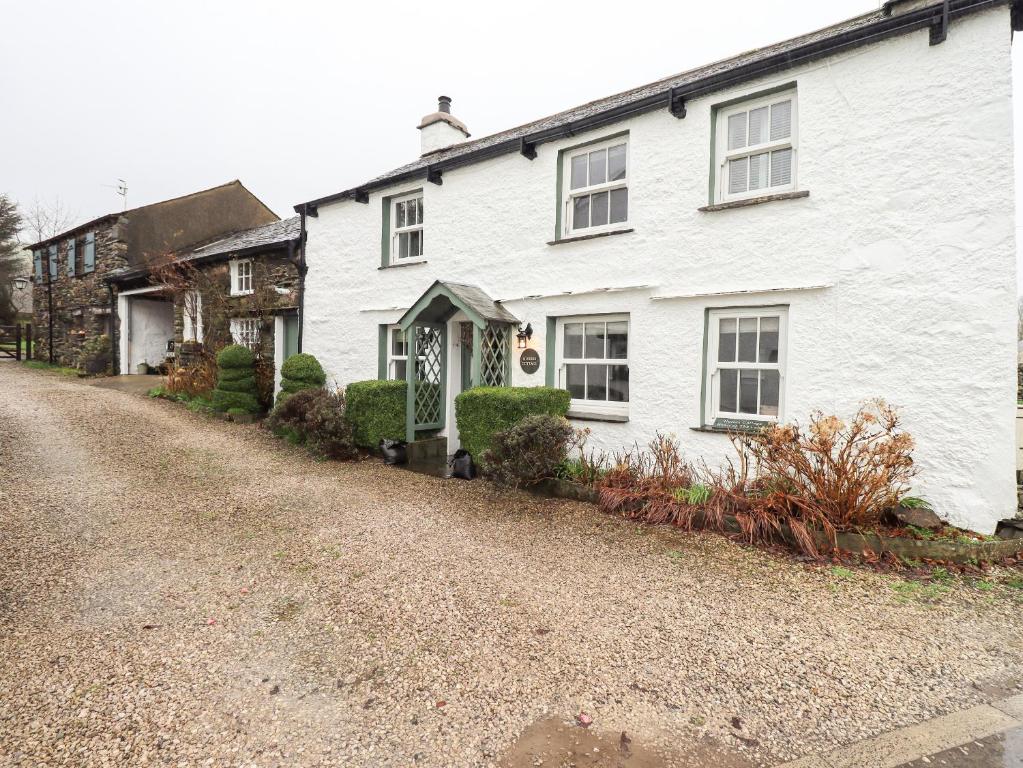 ein weißes Haus auf einer Schotterstraße in der Unterkunft Nurses Cottage in Hawkshead