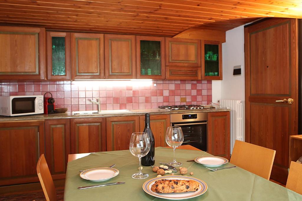 a kitchen with a table with a plate of food and wine glasses at Appartamento SassoMalenco in Chiesa in Valmalenco