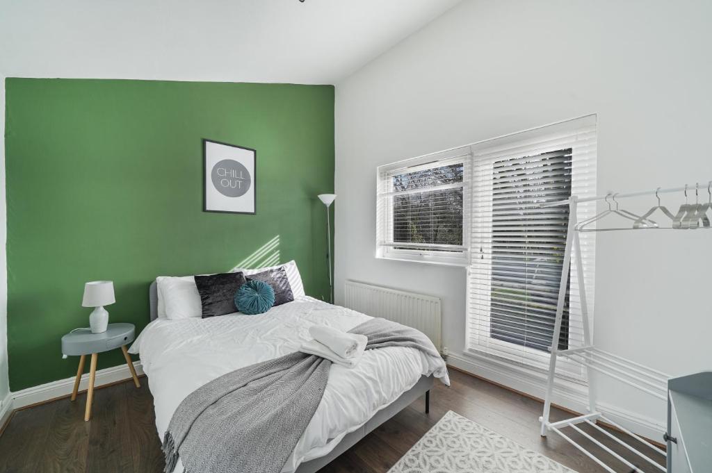 Dormitorio verde con cama y ventana en Stylish 3 BR House close to Streatham Hill station en Londres