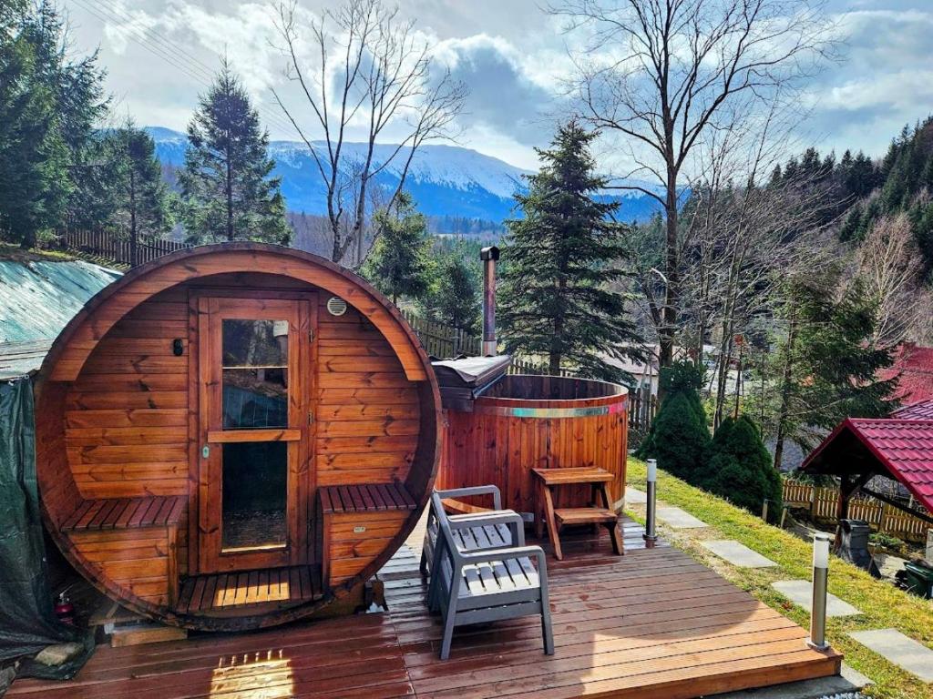 uma cabina de madeira com um banco e uma cadeira num deque em Zawoja 1895 sauna bania em Zawoja