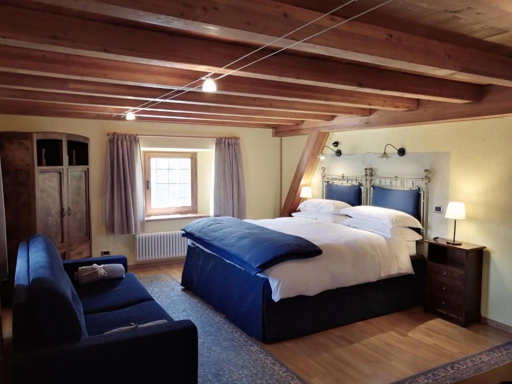 a bedroom with a large bed and a blue couch at La Thuillettaz B&B in Saint-Rhémy-en-bosses