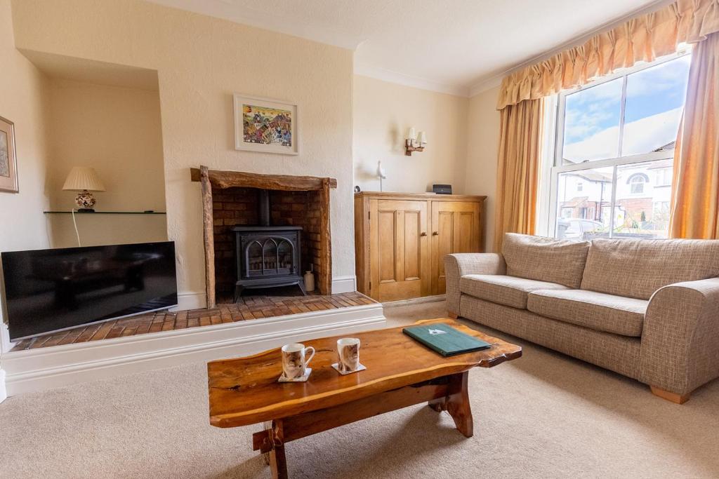 a living room with a couch and a fireplace at FIR TREE COTTAGE - Cosy 3 Bed Cottage in Penrhyn Bay with Beautiful Sea Views and Access to Snowdonia in Llandrillo-yn-Rhôs