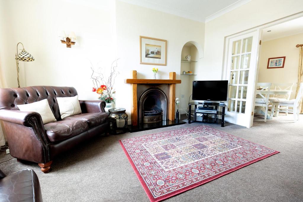 a living room with a leather couch and a fireplace at WILLOW COTTAGE - Cost 3 Bed Cottage in Penrhyn Bay with Sea Views with Access to Snowdonia in Llandrillo-yn-Rhôs