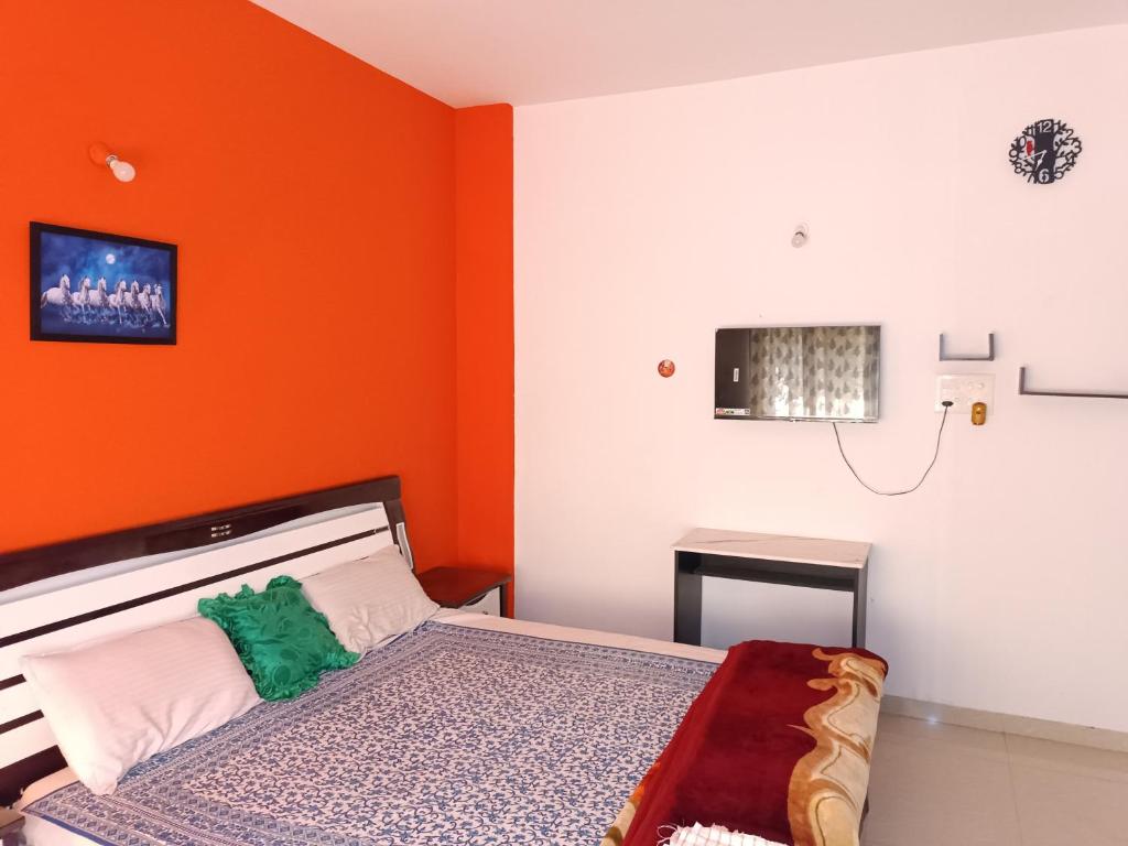 a bedroom with an orange wall and a bed at The Palm Greens in Pune