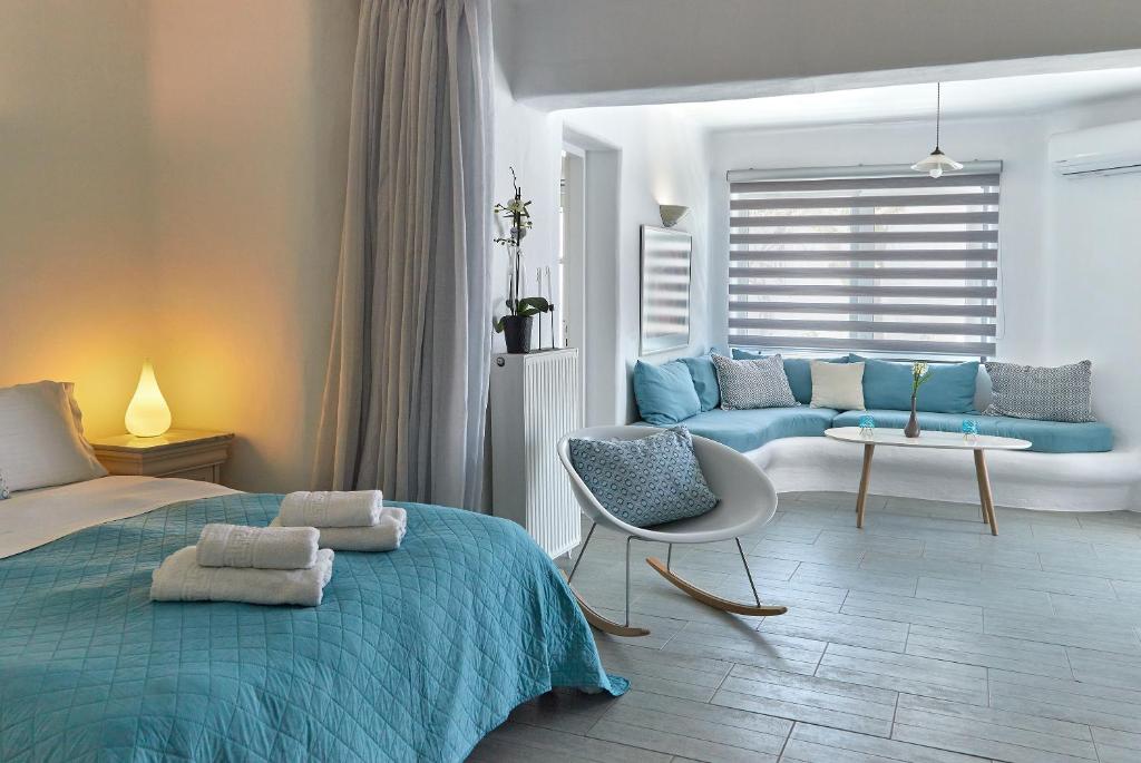 a bedroom with a blue bed and a couch at Yades House Paros in Naousa