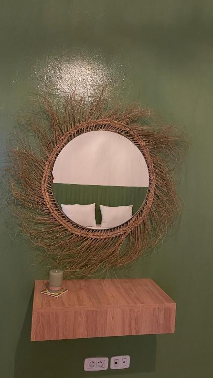 a round mirror on a green wall with a wooden shelf at Nomads Hostel Tunisia in Tunis
