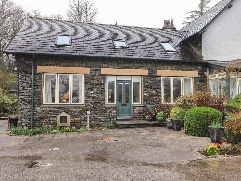 a stone house with a green door and windows at Middlerigg in Ambleside