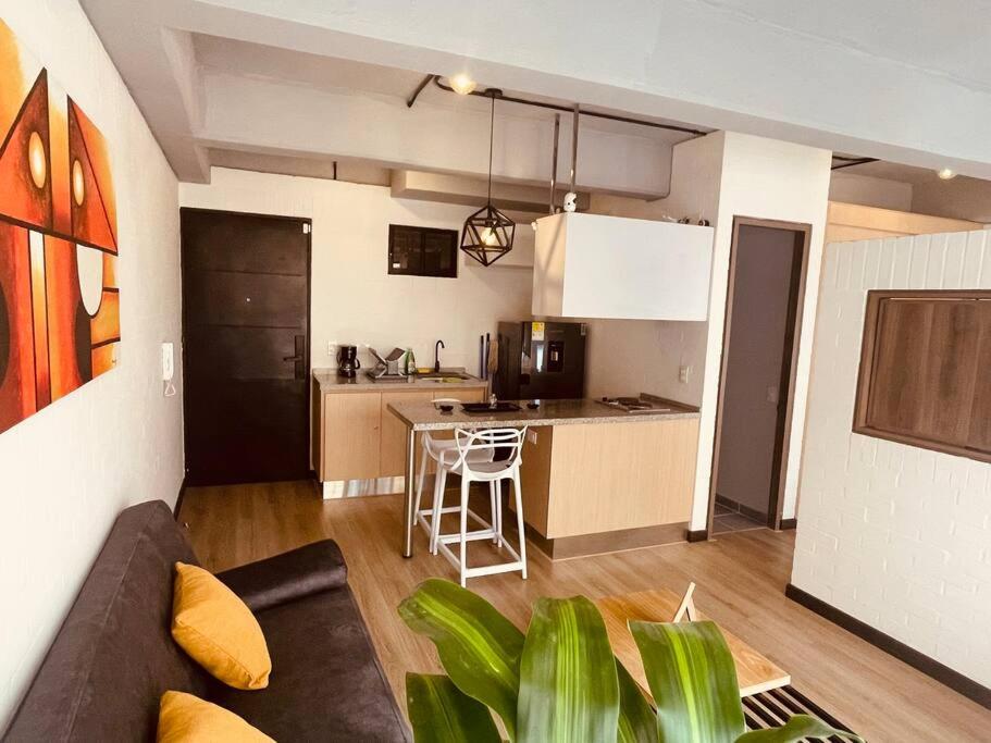 ein Wohnzimmer mit einem Sofa und einer Küche in der Unterkunft APTOPOR606 - Encantador apartamento tipo loft - Chapinero - Wifi - TV in Bogotá