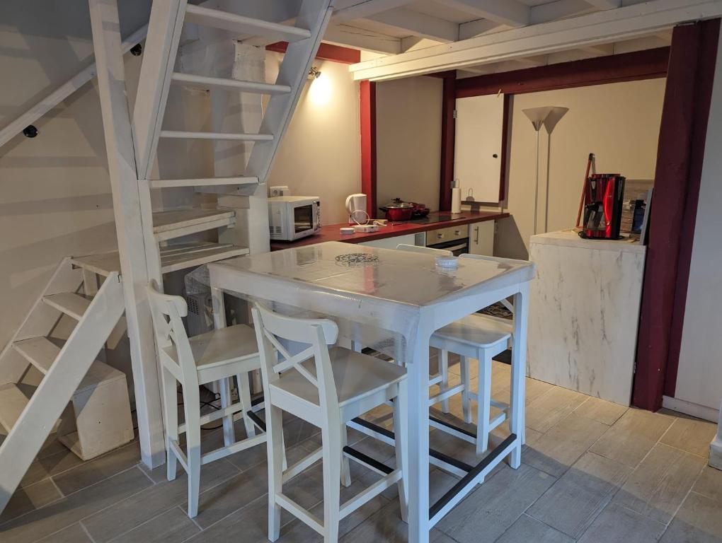 eine Küche mit einem weißen Tisch und weißen Stühlen in der Unterkunft charmante maison Normande in Livarot