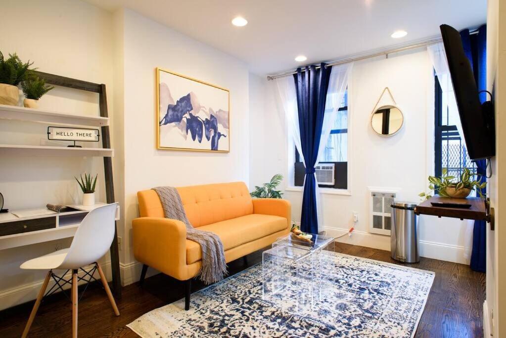 uma sala de estar com um sofá laranja e uma secretária em 69-3A Prime LES Modern Brand New 1BR em Nova Iorque