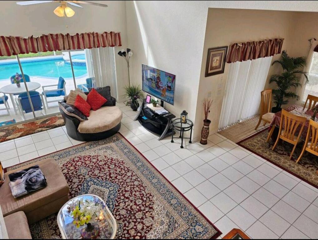 a living room with a couch and a table and a tv at Elysian deluxe villa in Davenport