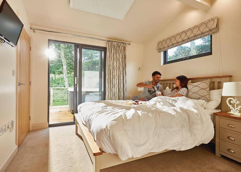 een man en vrouw zittend op een bed in een slaapkamer bij Cedar Retreats in Masham