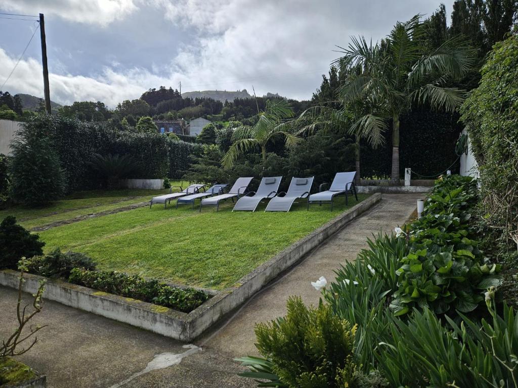 a row of white lounge chairs in a garden at Casa do Simão in Nordeste