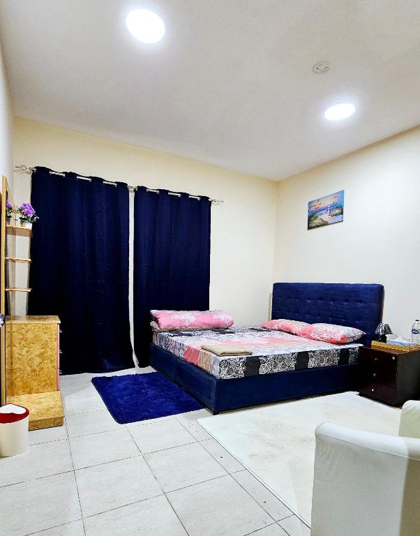 a bedroom with a bed and blue curtains in it at Anju's sweet Stay in Sharjah