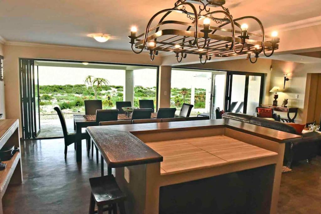 a dining room and living room with a chandelier at Hemel op Aarde Villa in Dwarskersbos
