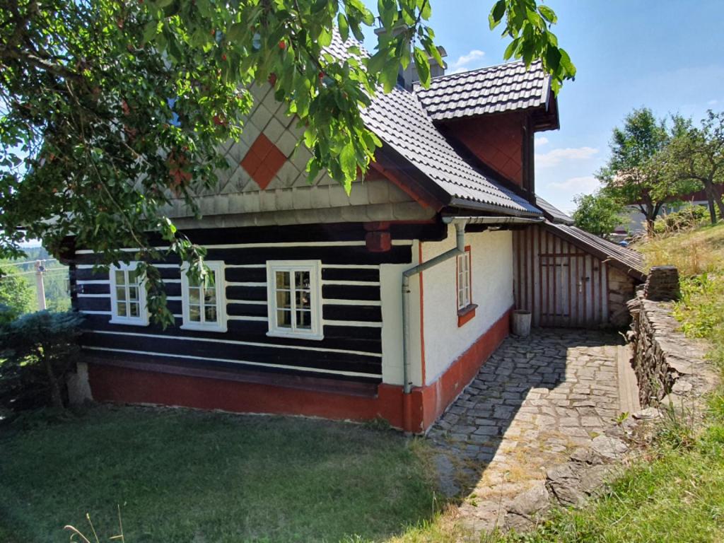 een klein huis met een zwart-witte gevel bij Roubenka Mia Jizerské hory in Tanvald
