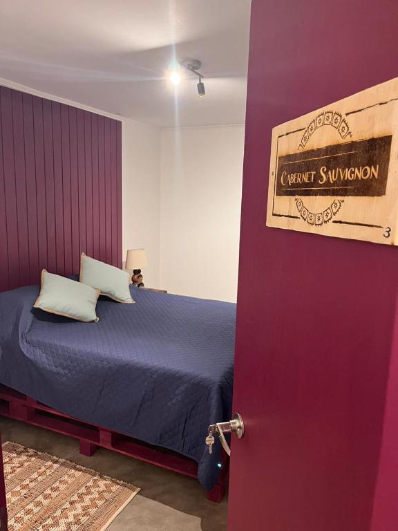 ein Schlafzimmer mit einem lila Bett mit einem Schild an der Tür in der Unterkunft Hostal Lodge Wine Colchagua in Nancagua