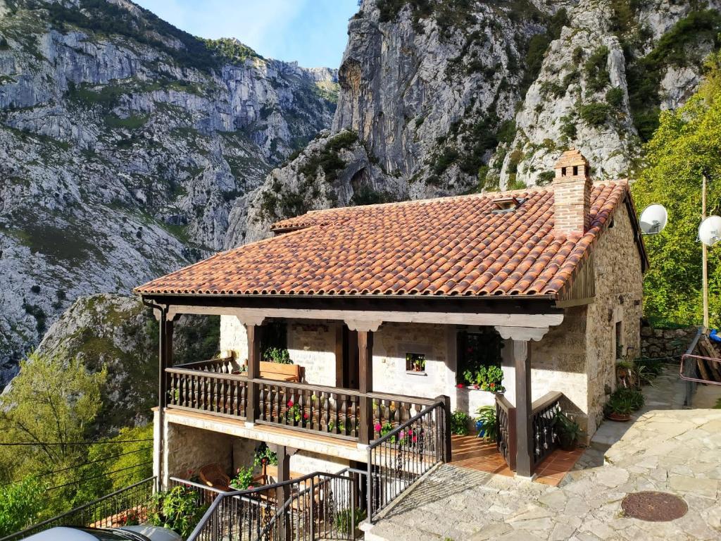 a small house with a balcony in front of a mountain at El Portal del Abuelo in Arenas de Cabrales