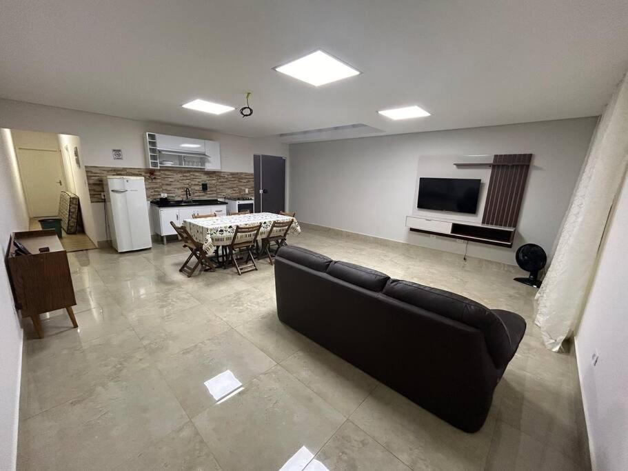 a living room with a couch and a table and a television at Oka Guaranis - casa aconchegante para grupos c ar condicionado e café da manhã in Santa Bárbara dʼOeste
