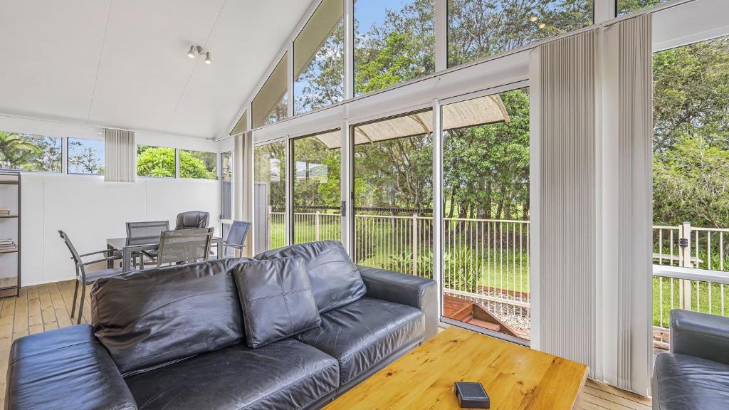 een woonkamer met een zwarte leren bank en een tafel bij Tranquil At Hibbard - 21 Hibbard Drive in Port Macquarie