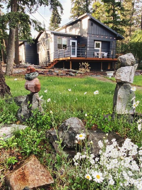 a house in the background with rocks and flowers at Woods Bay Get-A-Way in Bigfork