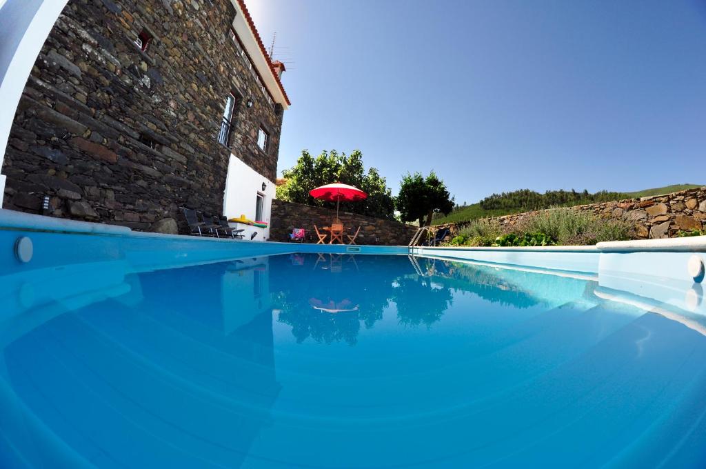uma piscina com um guarda-sol vermelho e um edifcio em Casa dos Hospitalrios em Alvaro