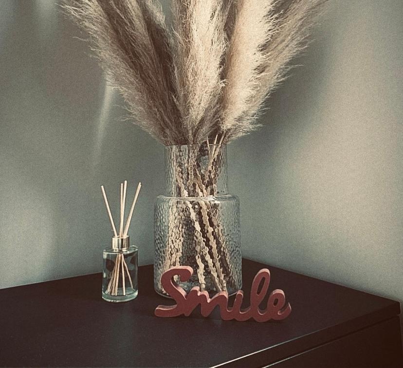 une table avec un vase rempli de plumes et une bougie dans l'établissement Appartement moderne avec garage et accès métro à 100m, à Villeurbanne