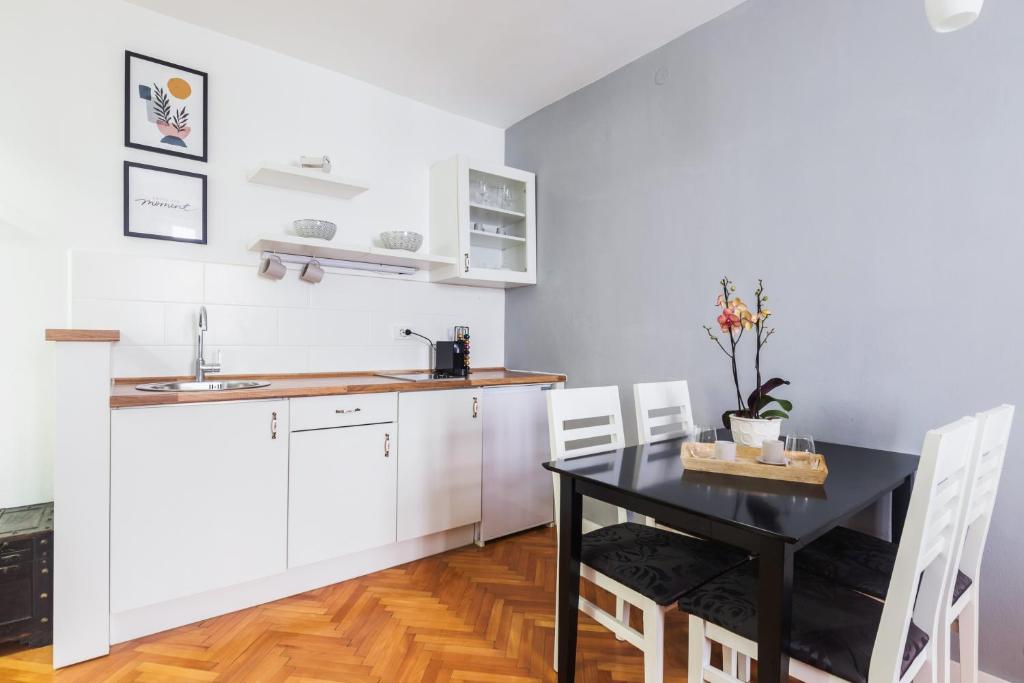 a kitchen with a black table and white cabinets at M&A Apartments in Zadar