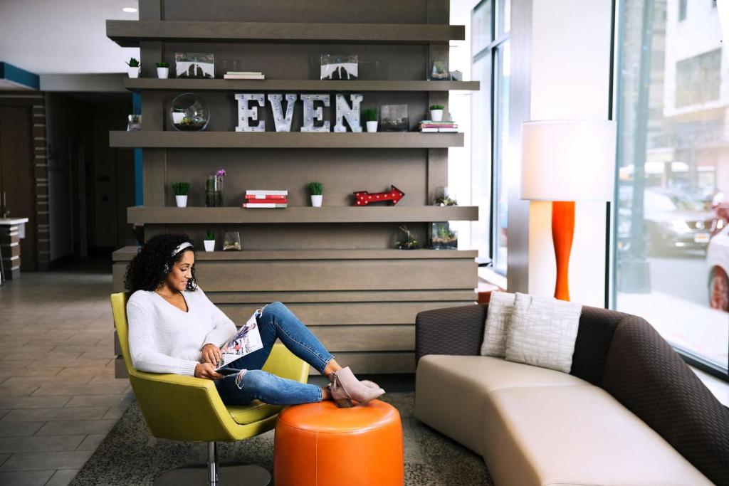 una mujer sentada en una silla leyendo un libro en EVEN Hotel Brooklyn, an IHG Hotel en Brooklyn