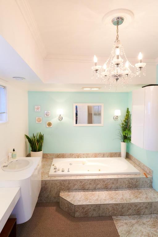 a bathroom with a tub and a sink and a chandelier at BALCON BLANC - Auberge à Chicoutimi, Saguenay in Saguenay