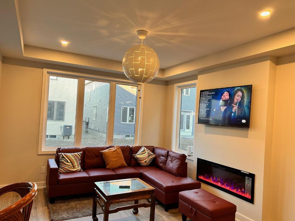 a living room with a brown leather couch and a tv at Moral’s Inn- Ottawa in Ottawa