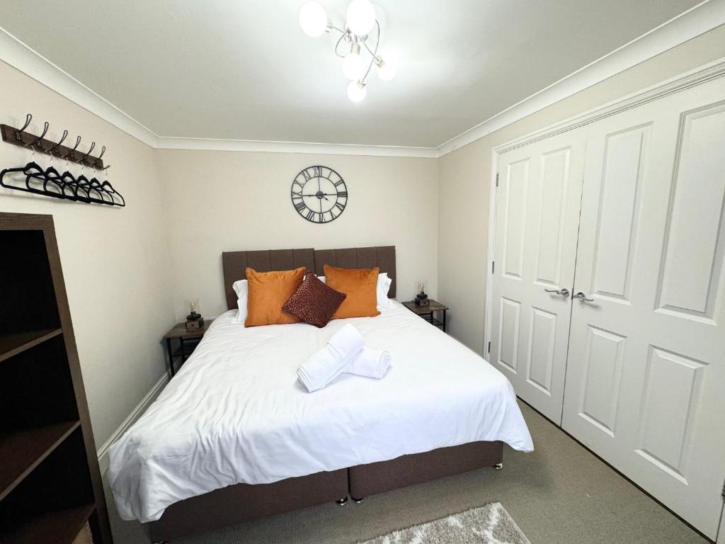 Un dormitorio con una cama con sábanas blancas y almohadas naranjas. en Riverview, en Colchester