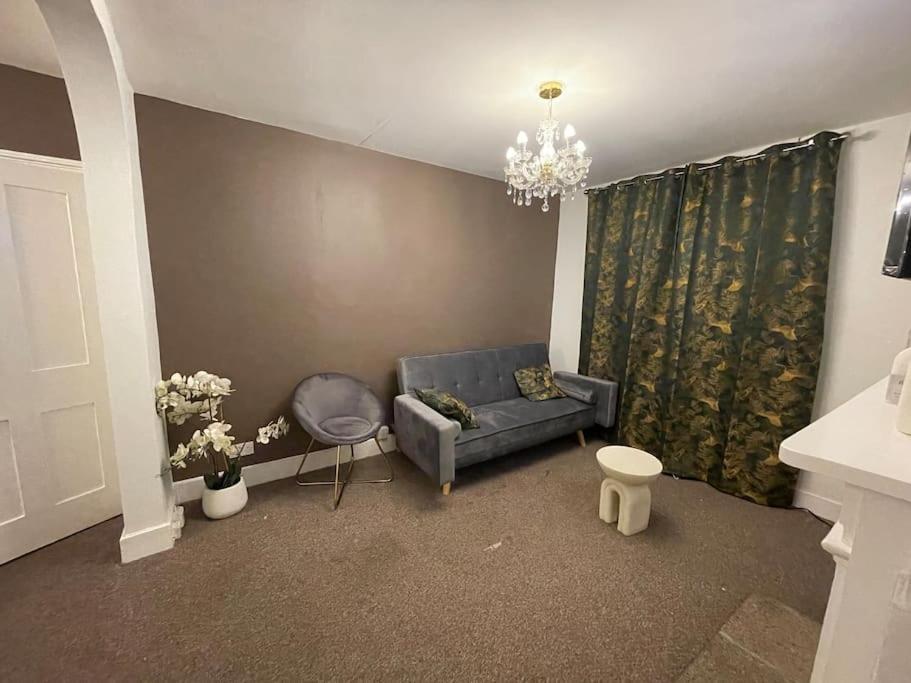 a living room with a blue couch and a chandelier at Modern 2 Bed in the heart of Maidstone in Kent