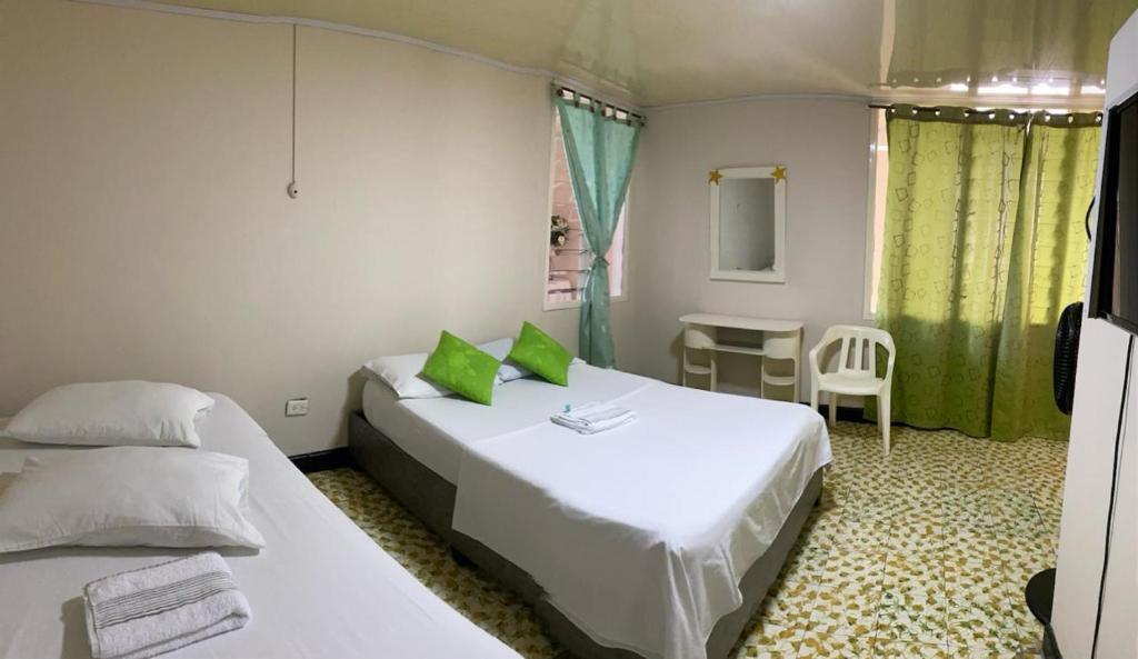 1 dormitorio con 2 camas, mesa y silla en Hotel La Estrella de la Mañana en Tuluá