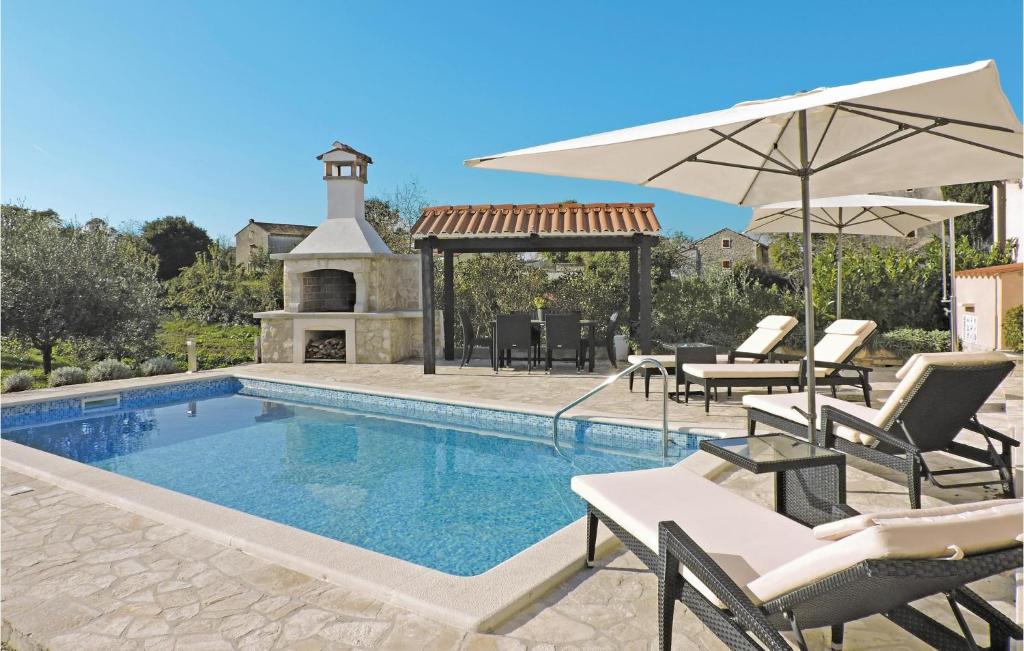 a swimming pool with chairs and umbrellas next to a house at Holiday Home Barban 60 in Barban