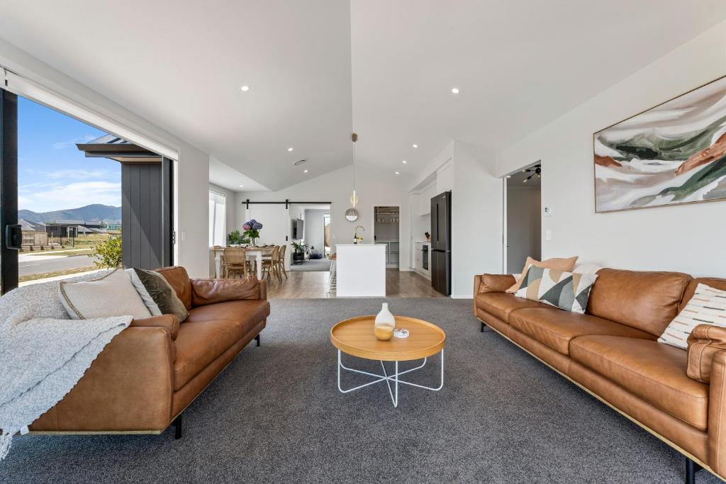una sala de estar con 2 sofás marrones y una mesa. en Harakeke Holiday Haven - Taupo, en Taupo