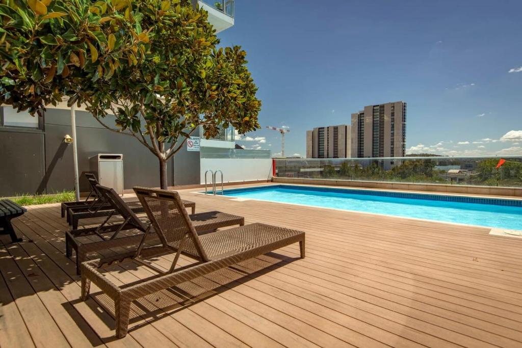 eine Terrasse mit Stühlen und ein Pool auf einem Gebäude in der Unterkunft Sensational City Apartment with Lake Views - Benjamin Way ACT in Canberra