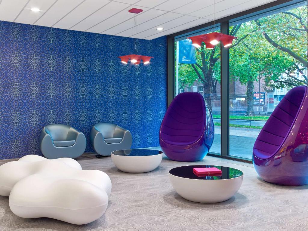 a room with purple and white chairs and windows at prizeotel Hannover-City in Hannover