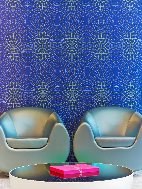 two chairs in a room with a blue wall at prizeotel Hannover-City in Hannover